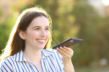 Happy woman dictating message on cell phone