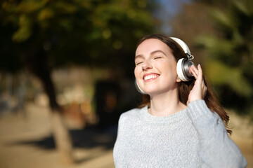 Happy woman listening music in a park with headphones