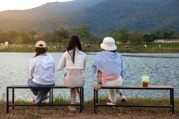 Group of friends is sitting beside the lake front of the mountains view on a beautiful day. relaxation concept