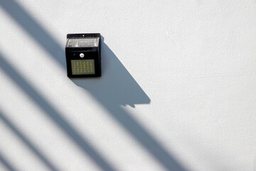 Fototapeta premium Solar-powered motion sensor light isolated on cement or concrete wall background, selective focus.
