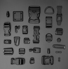 Accessories for clothes in black on a black background. Collage (fastex, rubber bands, buttons,...