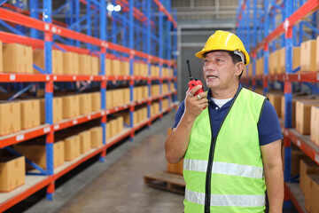 Warehouse workers man with hardhats and reflective jackets using walkie talkie radio controlling stock and inventory in retail warehouse logistics, distribution center