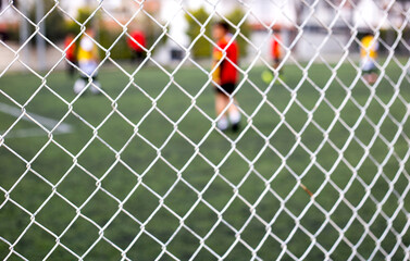 Soccer goal net with blurred players in background. Focus on net.