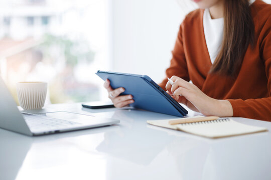 Asian teenage woman study online class at home or cafe by using tablet and laptop, video call with teacher and friends learning, university student studying online concept