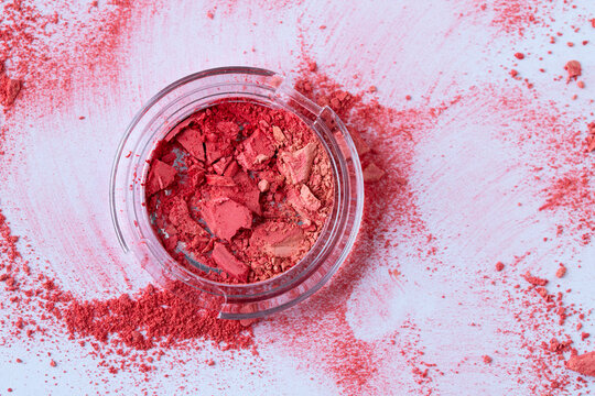 Top view of crush red pink coral eyeshadow or blush on pink background.