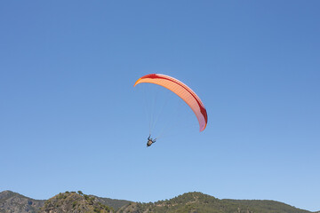 Paraglider in the blue sky. The sportsman flying on a paraglider.