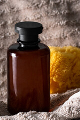 Cosmetic brown bottle shower gel and sea sponge atbeige towel texture background . Bath and bodu care concept shop and sale