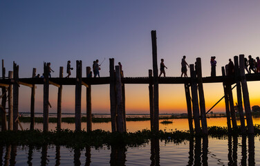 Amarapura, Myanmar - November 22, 2016: Unidentified people walk on U Bein bridge at sunset in Myanmar. U Bein bridge is the longest teak bridge in the world.