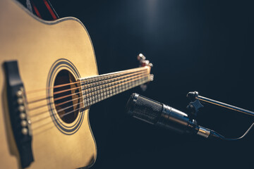 Acoustic guitar and microphone, recording in a music studio.