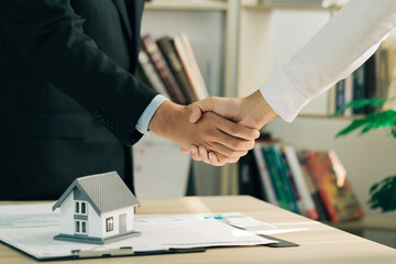 Real estate agents and customers shake hands to congratulate after signing a contract to buy a...