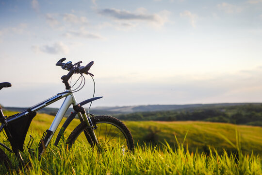Young man with bicycle on a rural road enjoying sunset