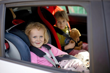 Cute children, boy and girl siblings, sitting in car seats in car, traveling. Family going to vacation