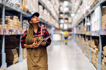 Portrait of smiling african american engineer woman order details checking goods and supplies on shelves with goods background in warehouse.logistic and business export