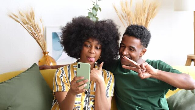Smiling black cuple taking selfie on smartphone