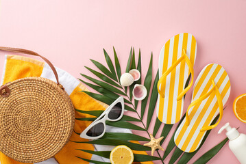Stylish summer getaway concept. Top view flat lay of yellow striped flip-flops, towel, green palm leaves, vintage sunglasses, bag on pastel pink background with empty space for text or advert