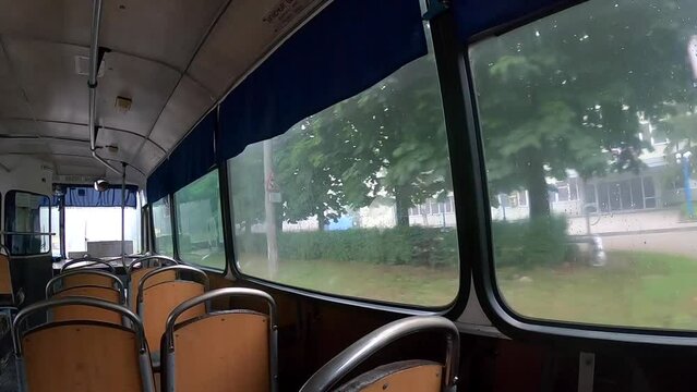 View from window of moving bus. Different buildings of city in window of moving bus. Inside empty old authentic public transport bus in city. Wide angle. Transport travel moving. Soviet-style.