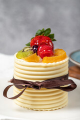 Fruit cream cake. Strawberry, pear, kiwi and raspberry cake covered with white chocolate on a dark background. Patisserie desserts. Close up