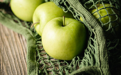 Close-up, green apples in a mesh shopping bag.