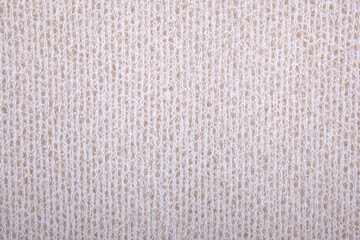 Knitted background, wallpaper. Beige, light beige knitted fabric texture. Soft material. Brown, beige and white close up photo for texture, graphic design and creative backgrounds. Acrylic knit detail