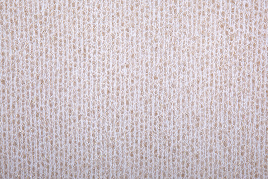 Knitted background, wallpaper. Beige, light beige knitted fabric texture. Soft material. Brown, beige and white close up photo for texture, graphic design and creative backgrounds. Acrylic knit detail