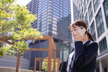 オフィス街で電話をする日本人ビジネスウーマン