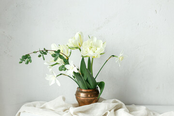 Beautiful white tulips and daffodils on wooden table against rustic wall. Happy Mothers day....