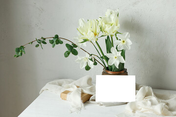 Happy Mothers day. Beautiful bouquet in vintage vase, gift box and empty card on rustic wooden table. Greeting card mockup and stylish white spring tulips. Women's day. Space for text