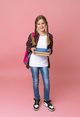 Naklejka premium Smiling little blonde girl 10-12 years old in school uniform with backpack holding books isolated on pastel pink background studio portrait. The concept of children's lifestyle. Education at school.
