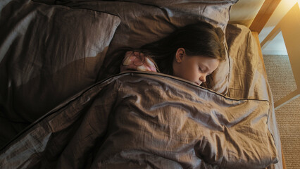 Sleeping kid night rest. Sweet dreams. Relaxed peaceful tranquil little girl sleeping in cozy bed late in dark home bedroom.