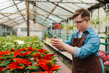Man with down syndrome taking picture of flowers while working in greenhouse