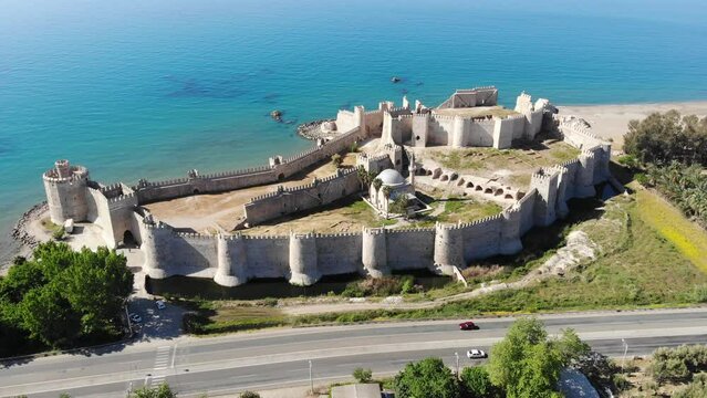 Picturesque drone view of remains of medieval castle Mamure Kalesi in Bozdogan village on coast near turquoise waters of Mediterranean Sea on sunny spring day, Turkey