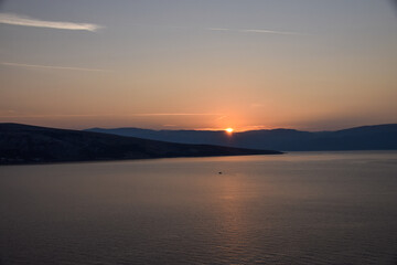 Vibrant sunset descending on the horizon, sea in golden colors, small waves gently touching the sands,