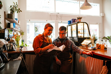 Smiling woman training man with down syndrome for work in cafe