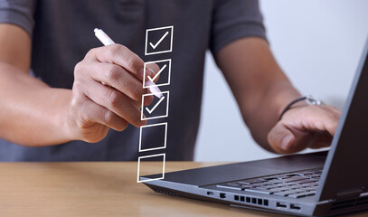 Business performance checklist concept, businessman using laptop doing online checklist survey,...