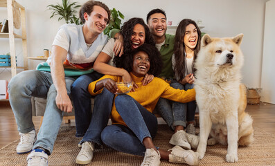 group of young millennial girls on sofa with dog - multiracial people having fun - roommates, students