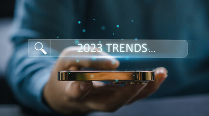 Human hand use smartphone searching keyword of 2023 trends, business trends, fashion trends, start...