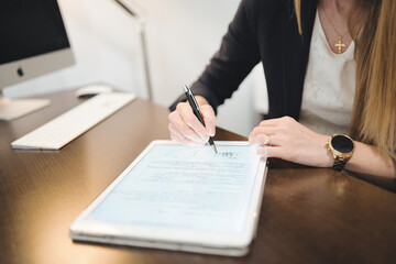 Close-up of a psychologist signing a document on a digital tablet in her office.