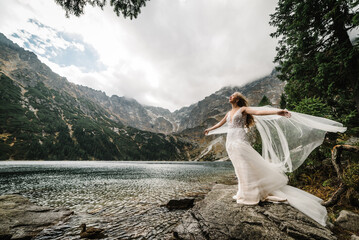 Bride standing on the stony shore of the Sea Eye lake in Poland. Scenic mountain view. Morskie Oko. Tatra mountains. © Serhii