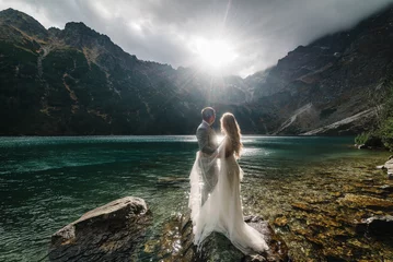 Foto op Plexiglas Tatra The bride and groom near the lake in the mountains. A couple together against the backdrop of a mountain landscape. Morskie Oko (Sea Eye) Lake. Tatra mountains in Poland.