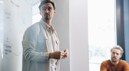 Professional man standing in front of his team in a meeting, engaging them in a discussion on product development