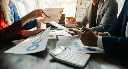 Business documents on office table with smart phone and calculator digital tablet and graph business with social network diagram and two colleagues discussing data working in the office.