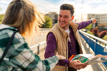 young tourists smile as they cross the bridge and use the map, trying to get back on track