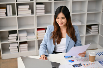 Obraz na płótnie Canvas Beautiful Asian businesswoman working on financial report and using laptop art her desk