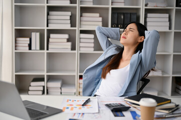 Exhausted Asian businesswoman putting her hands over head, resting in her office.