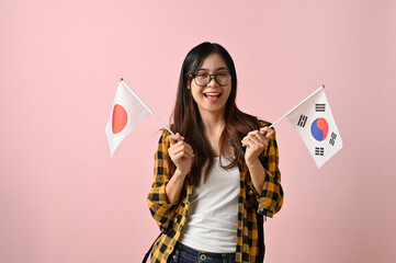 Pretty Asian female college student holding the flags of Japan and Korea. Exchange student
