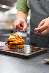 chef hand cooking chickenburger on restaurant kitchen