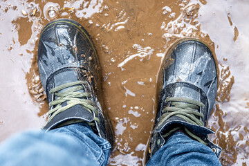 View from above on pair of trekking shoes in a mud.