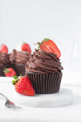 Chocolate cupcake with dark chocolate buttercream and strawberries, double chocolate cupcakes with american buttercream, tall swirl frosting on a cupcake with a strawberry