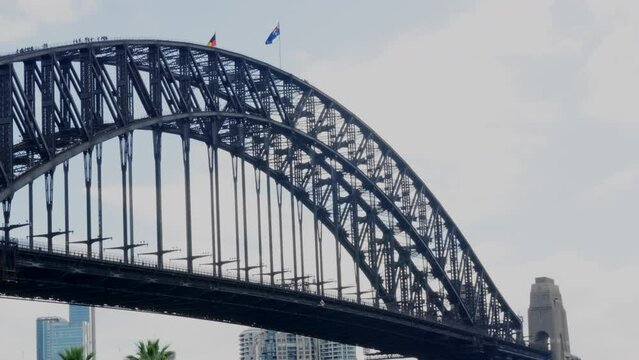 Tourists climbing over Sydney Harbour Bridge as the Aboriginal and Australian flags fly overhead, in Australia