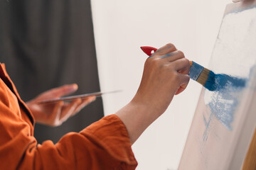 Close up of artist hands with brush painting picture on canvas. Art, creativity and people concept